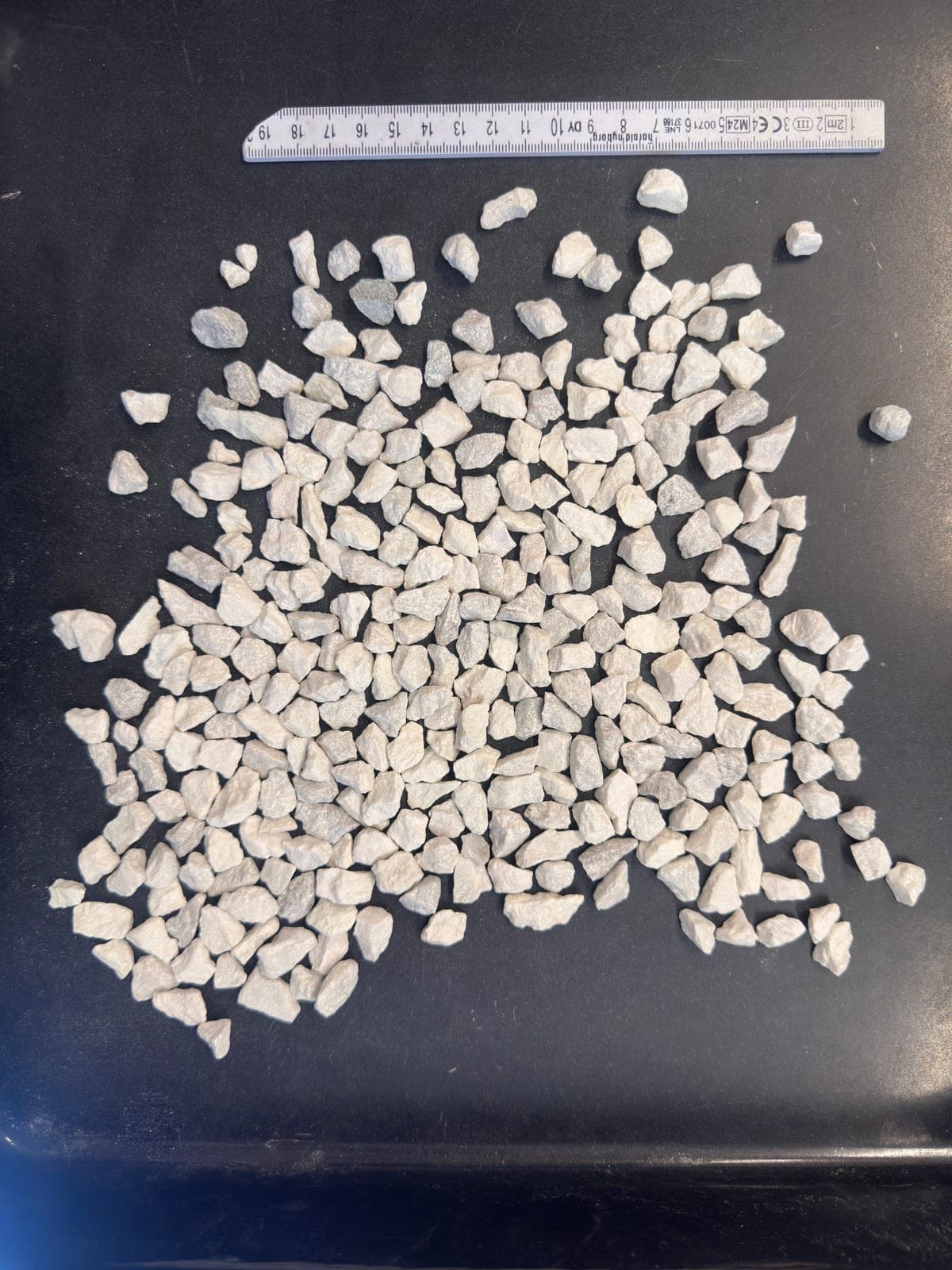 Source photo of a 4–8 mm white granite sample on a dark tray with a ruler for scale